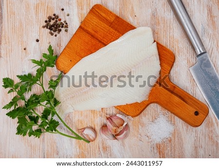 Raw halibut fillet, garlic, parsley on wooden table. Ingredients for cooking