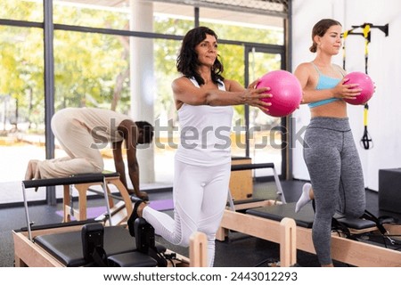 Portrait of two young sporty woman during group core training with bender ball at gym. Healthy lifestyle and pilates concept
