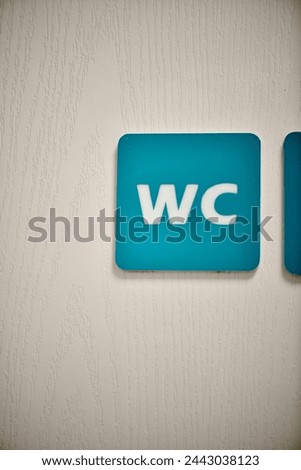 Blue colored toilet sign that says wc on a white door.