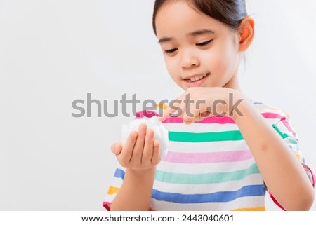 Cute Asian girl, holding foam, washing her face, on a white background.