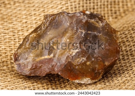 Stone scraper made of red-yellow chalcedony, Stone Age tool Royalty-Free Stock Photo #2443042423