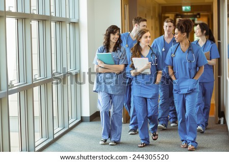 Medical students walking through corridor at the university Royalty-Free Stock Photo #244305520