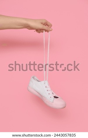 Female hand with stylish gumshoe on pink background Royalty-Free Stock Photo #2443057835