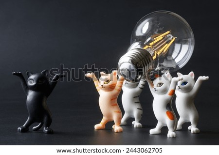 Funny toy kittens carry a modern energy-saving LED lamp in their paws. An educational concept for saving electricity. Electrification. Toy world. Photo. Close-up