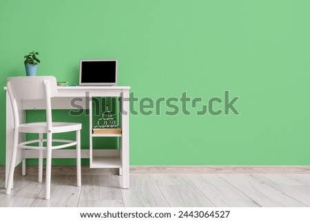 Stylish workplace with modern laptop near green wall