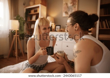 Tattooed man and his beautiful wife enjoying coffee in bed