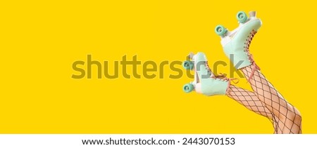 Legs of woman in roller skates on yellow background with space for text Royalty-Free Stock Photo #2443070153