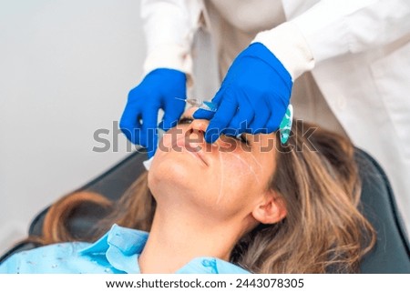 Doctor cleaning the injection area with a cotton pad on the patient's face before administering hyaluronic acid