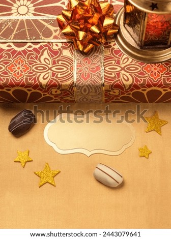 Beautiful photo for the occasion of Eid celebration. A blank golden tag or plaque to write message with Ramadan lantern and gift box.
