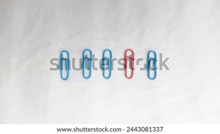 Concept of new idea, uniqueness, and creative thinking as a symbol of innovation and inspiration metaphor as a group of paper clips but one paper clip has different color than the others