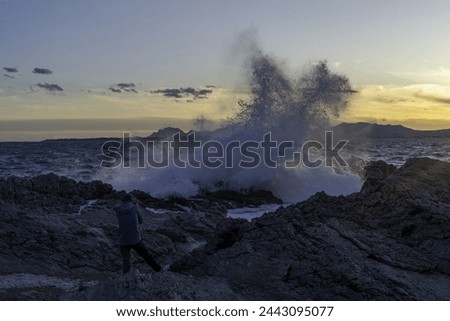 A photographer shoots waves crashing on cliff. High quality photo