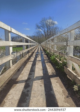 Kissing gate walk a bridge in Alfristston UK over the river Cuckmere with blue sky 27 March 2024
