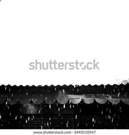 This black and white photo captures rain cascading down a textured metal roof. The raindrops create a mesmerizing flow, perfect for evoking a sense of peace and tranquility.