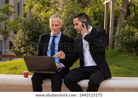 Two businessmen with laptop in hand looking at the results of the project.