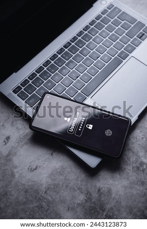 Smartphone resting on laptop with secure access to user's personal information on screen. Sign in or register with username and password. Cyber security and data protection.