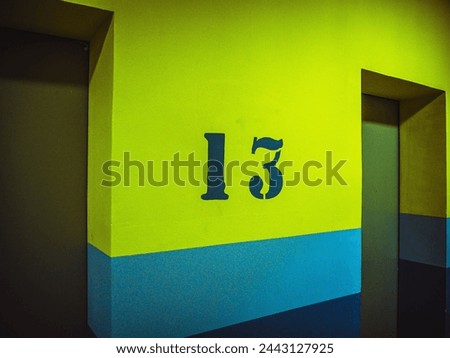thirteen floor with number on yellow wall near lift, elevator.