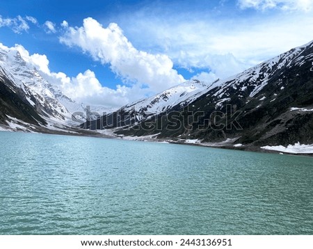 Scenic winter landscape of a stunning snow-covered lake nestled in majestic mountains. Serene beauty of nature in tranquil surroundings. Perfect for winter-themed designs.