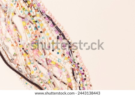 Multicolored chains of beads, pearls and natural stones on a beige background. Concept with copy space.