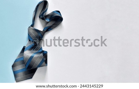 Father's Day concept. Top view photo of heart shaped blue necktie on a blue and white background with copy space. Horizontal banner. Mockup for greeting card 