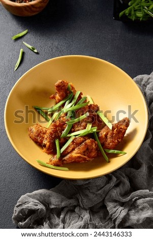 Asian-style buffalo chicken wings on a golden plate with green onions, vibrant and appetizing.