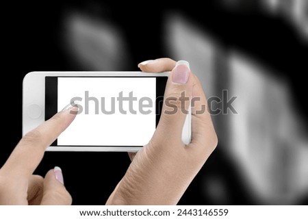 Human hand holding modern smartphone with blank screen.