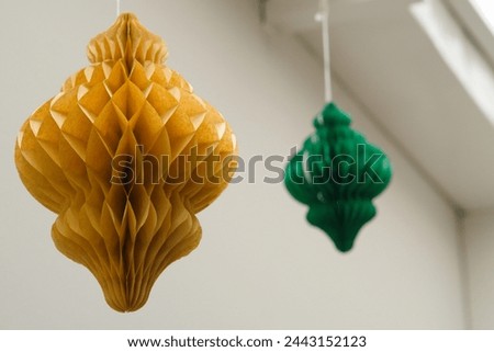 Colorful Paper Ornaments: Yellow and Green Adornments Dancing from the Rooftop Royalty-Free Stock Photo #2443152123