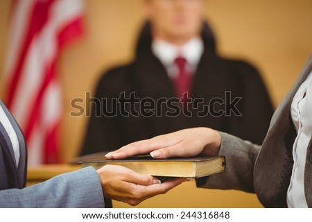 Witness swearing on the bible telling the truth in the court room Royalty-Free Stock Photo #244316848