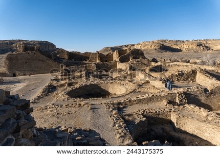 Chaco Culture National Historical Park in New Mexico. Pueblo del Arroyo great house, kivas, and woman in blanket. Chaco Canyon was a major Ancestral Puebloan culture center and has many pueblos.  Royalty-Free Stock Photo #2443175375