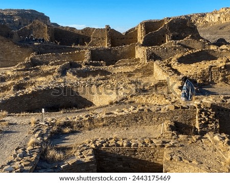 Chaco Culture National Historical Park in New Mexico. Pueblo del Arroyo great house, kivas, and woman in blanket. Chaco Canyon was a major Ancestral Puebloan culture center and has many pueblos.  Royalty-Free Stock Photo #2443175469