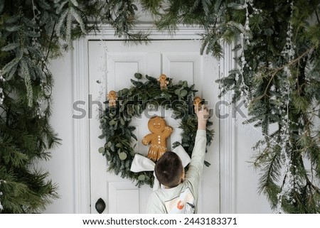 a very cute decorative gingerbread man and a little boy who decorates the front door of the house with it