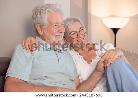 Carefree relaxed senior couple sitting on sofa, recollecting good memories or planning common future, enjoying peaceful moment together at home. Royalty-Free Stock Photo #2443187603