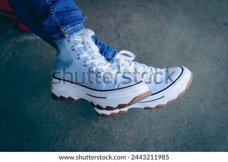 Light blue sneakers worn by a woman.