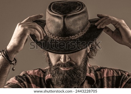 Cowboy style. Handsome young man adjusting his cowboy hat. Cowboys in hat. Handsome bearded macho. Man unshaven cowboys. American cowboy. Leather cowboy hat. Royalty-Free Stock Photo #2443228705