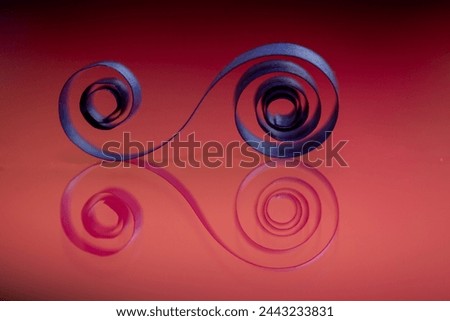 A piece of orange paper is curled into a spiral shape. The image has a warm, inviting mood, and the orange color of the paper adds a sense of energy and excitement