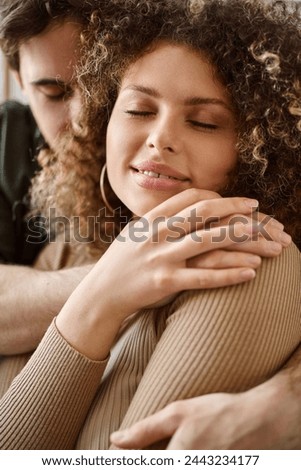 Closeup image of curly young woman and brunette man sharing a heartfelt hug in bedroom