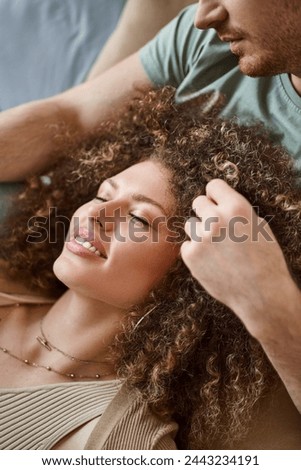 Closeup image of man touching his girlfriend hair in bed, smiling and enjoying time together at home