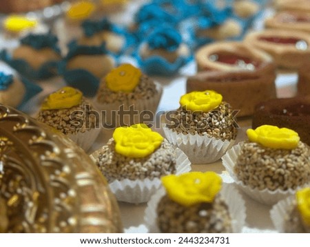 Traditional sweets cookie on holiday of henna. Arabic and Jewish desert with nuts and sesame. yellow and blue cream on cookie on table. gold traditional utensils.