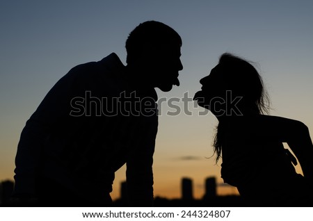 Young couple showing each other tongue against the evening city Royalty-Free Stock Photo #244324807