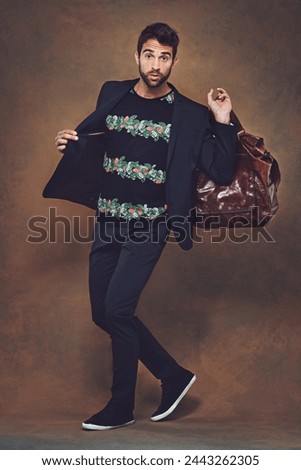 Man, fashion and stylish outfit in studio on brown background, confident male person, model and trendy bag in hand. Leather luggage, businessman and travel abroad for work and business clothes Royalty-Free Stock Photo #2443262305