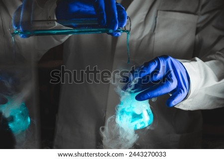 Smoky experiments with blue colour solution.  Scientist working on chemical reaction, generating thick smoke from a glass flask. Copyspace