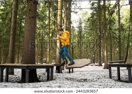 11 year old boy on a rope playground going through an obstacle course in a snow park	