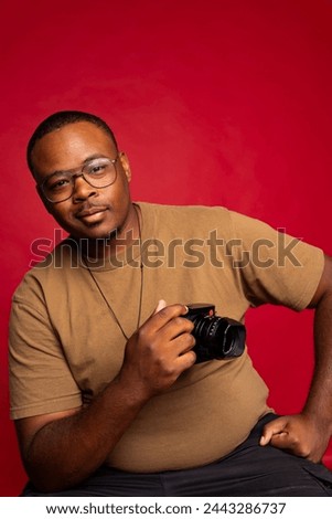 Black man smiling and holding camera in the studio