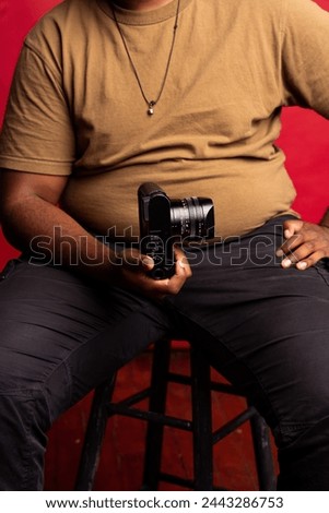 Black man holding a photography camera in the studio