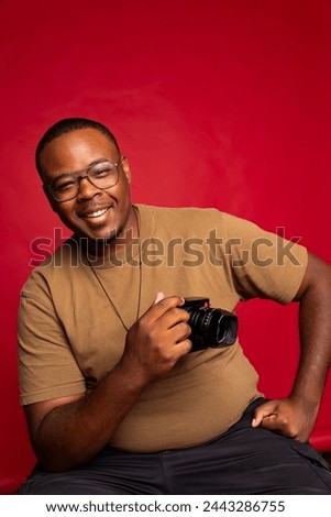 Black man smiling while holding camera in a photography studio
