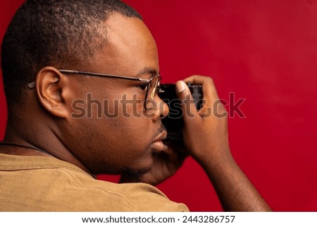 Black man looks over shoulder while taking a photograph with a photography camera in the studio