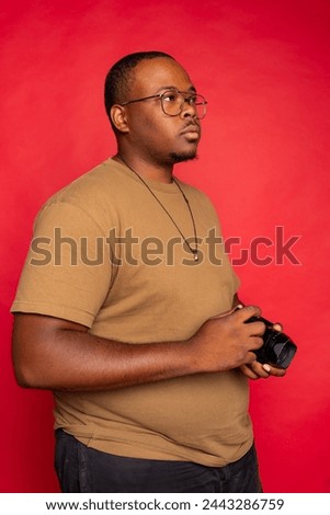 Black man holding a photography camera and looking into the distance 