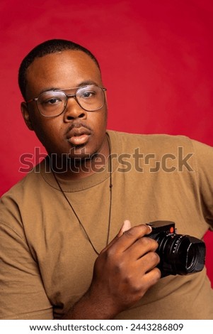 Black man photographer poses for a photograph while holding a photography camera in the studio