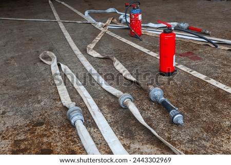 Red fire extinguisher cylinder with unwound fire hoses. Royalty-Free Stock Photo #2443302969