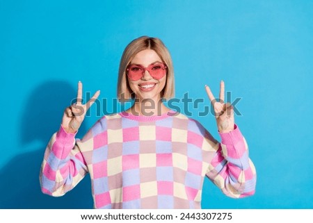 Photo portrait of pretty young girl sunglass celebrate party show v-sign wear trendy pink outfit isolated on blue color background