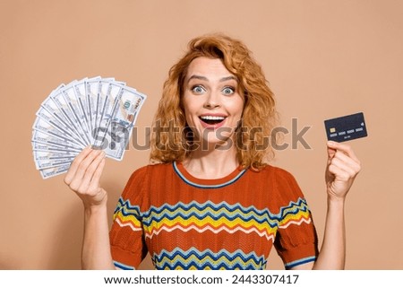 Photo portrait of lovely young lady hold money dollars credit card dressed stylish striped garment isolated on beige color background